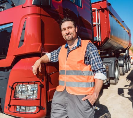 Truck driver leaning on his truck happy to have truck insurance